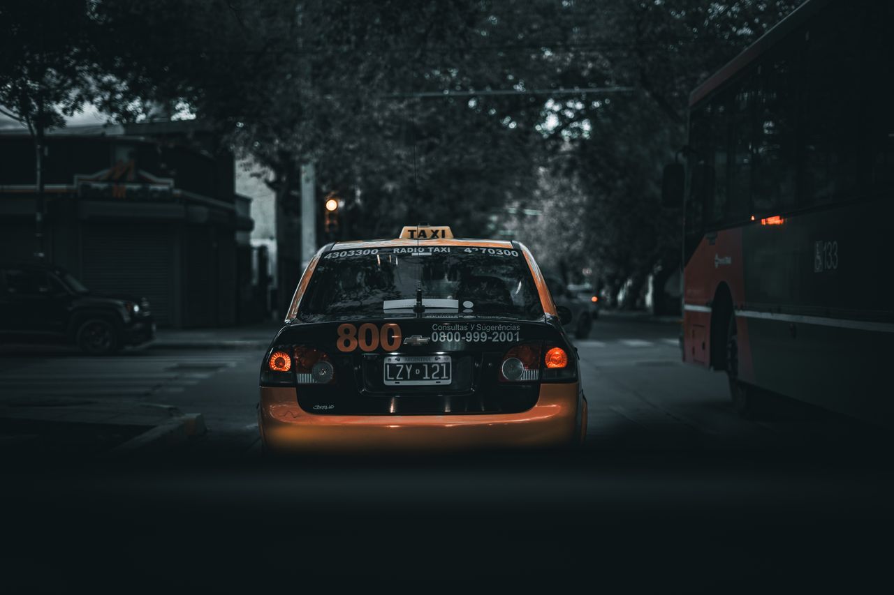 about-01 Moody city street with a taxi and bus at night, showcasing urban transportation.