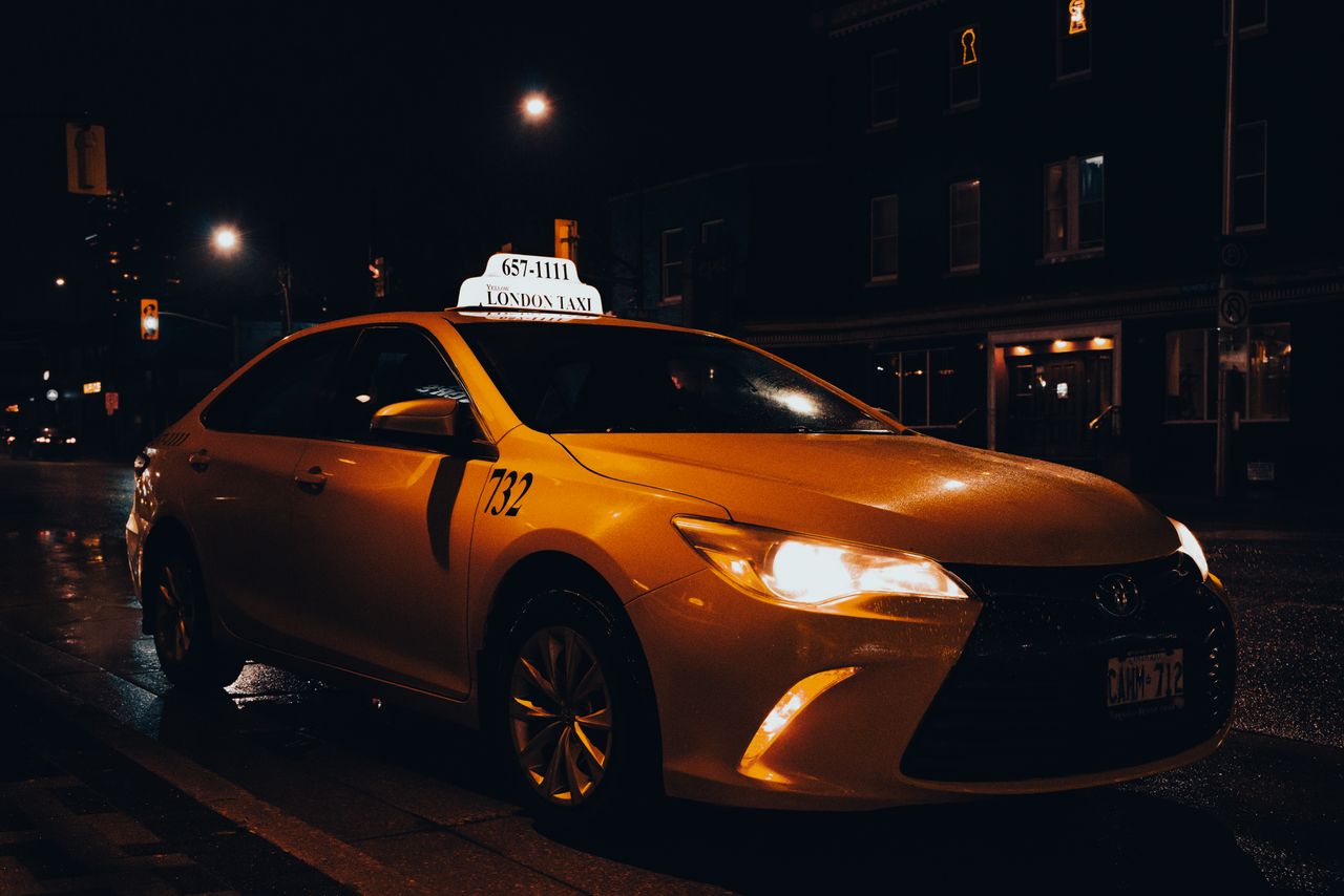 gallery-2 A yellow taxi waiting at night in London, Ontario, Canada. Urban transportation captured with street lights.