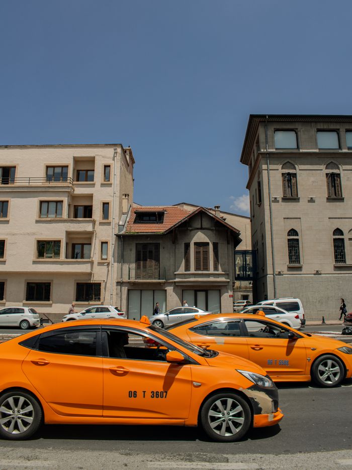 contact-img Street view of yellow taxis in front of historic buildings under clear blue sky.