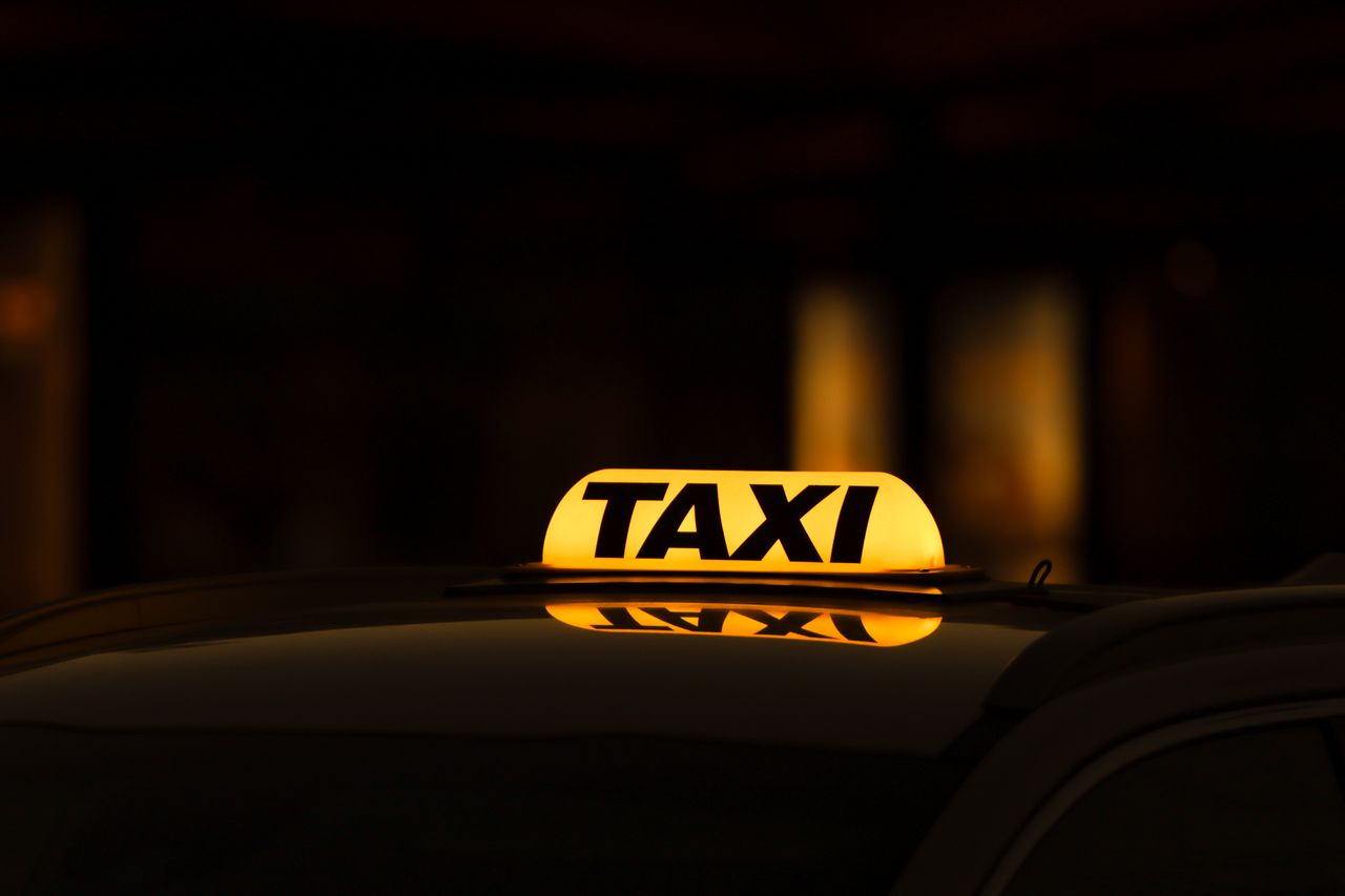 about-img Yellow taxi sign glowing in Gothenburg night, perfect for urban travel themes.