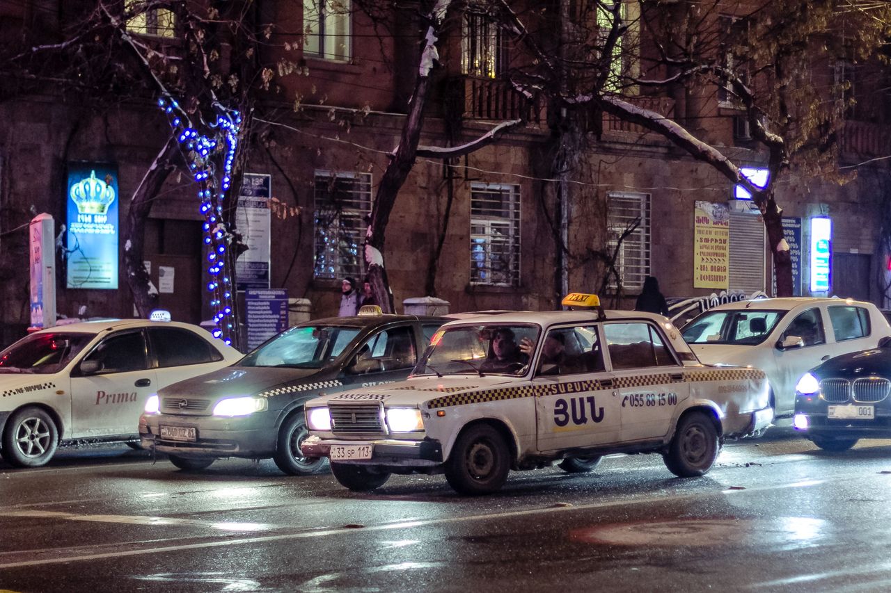 services-04 Urban nighttime scene showing taxis, traffic, and city lights on a bustling street.